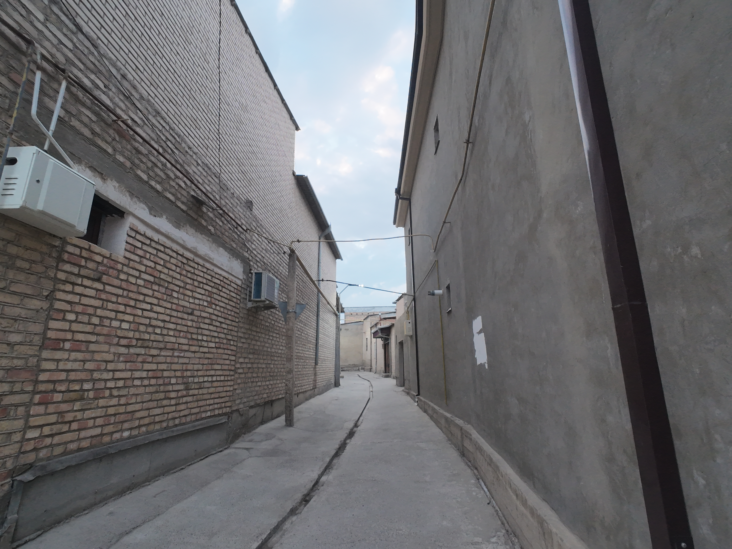Quiet alleyway inside Bukhara Old City, Uzbekistan, lined with traditional brick and plaster buildings